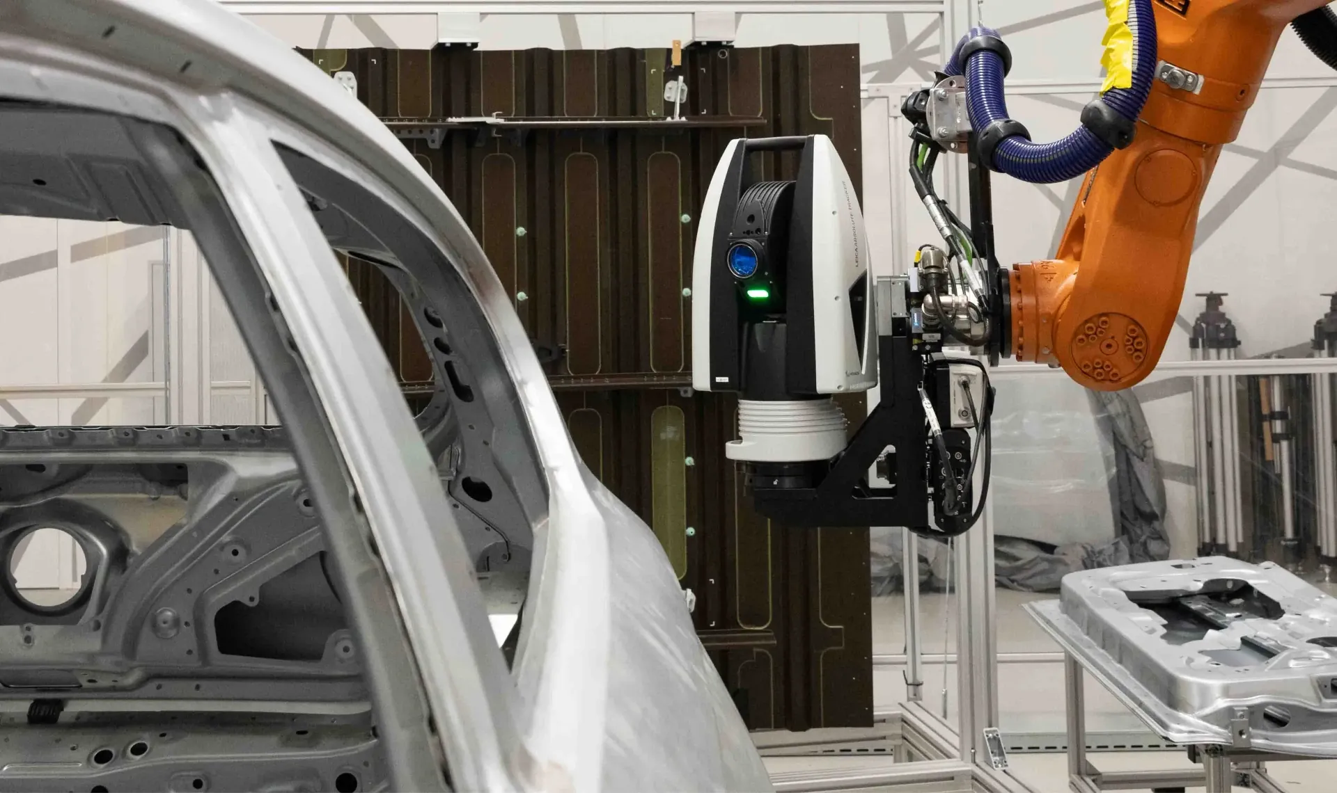 Leica Absolute Tracker montert på robotarm som måler bilkarosseri i industrielt miljø