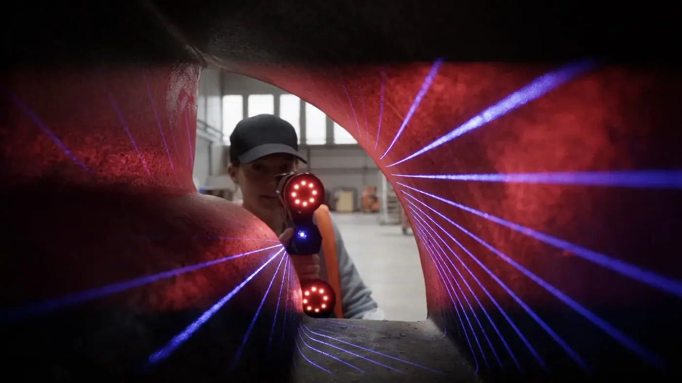 Operatør skanner innsiden av en stor støpt del med MARVELSCAN, blå laserlinjer over overflaten